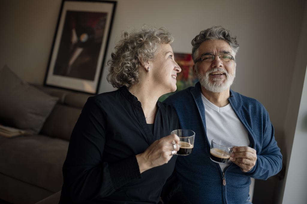 An older couple sitting close together on a sofa at home, talking quietly.